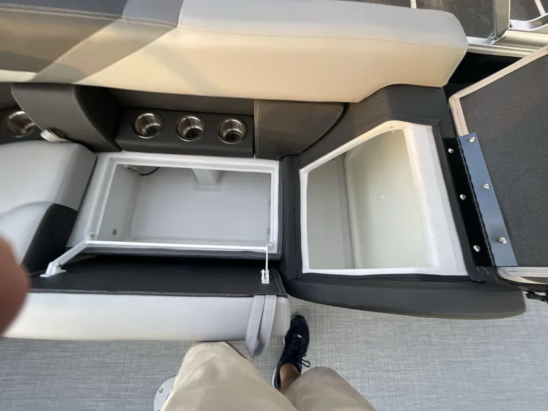 Slide: The Image of 2025 South Bay S224RS boat interior with open storage compartments and cup holders. - 16