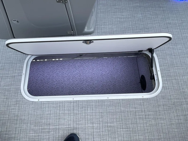 Slide: The Image of Open storage compartment on 2025 South Bay S224RS boat with gray flooring. - 22