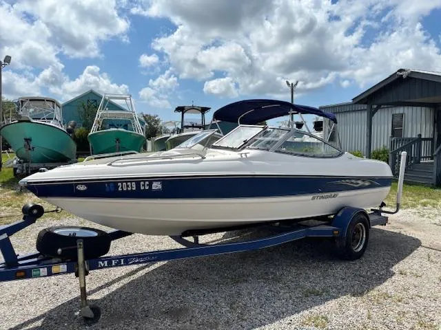 Slide: The Image of 2006 Stingray 185 LS/LX boat on trailer, parked outdoors under a partly cloudy sky. - 1
