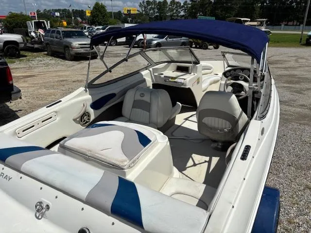 Slide: The Image of 2006 Stingray 185 LS/LX boat with blue canopy and white interior, parked outdoors. - 6