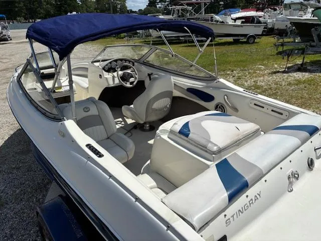 Slide: The Image of 2006 Stingray 185 LS/LX boat with blue canopy and white interior, parked outdoors. - 7