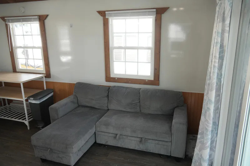 Slide: The Image of 2024 Catamaran Aqua Lodge interior with gray sectional sofa, wooden accents, and large windows. - 12