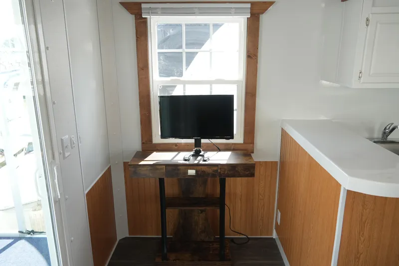 Slide: The Image of 2024 Catamaran Aqua Lodge interior with desk, monitor, and window view. - 13