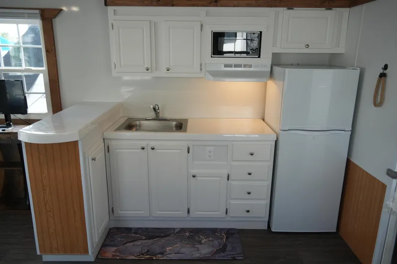 Slide: The Image of 2024 Catamaran Aqua Lodge kitchen with white cabinets, sink, fridge, and microwave. - 14