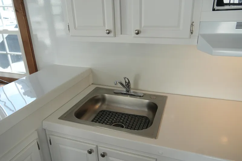 Slide: The Image of Modern kitchen sink in 2024 Catamaran Aqua Lodge with white cabinetry and stainless steel fixtures. - 15