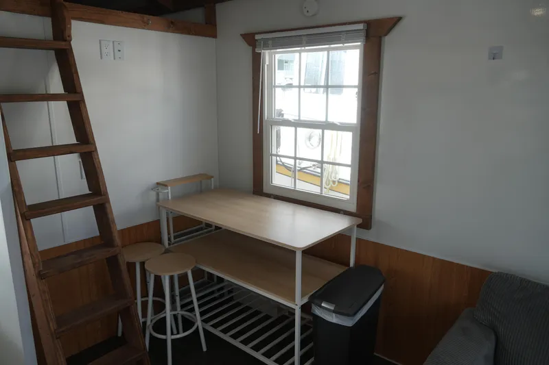 Slide: The Image of 2024 Catamaran Aqua Lodge interior with wooden ladder, dining table, stools, and window. - 18