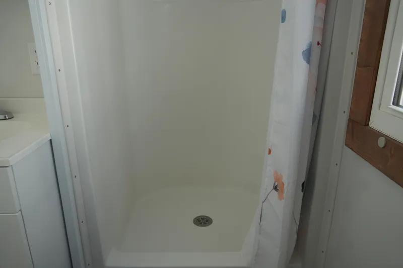 Slide: The Image of Shower area in 2024 Catamaran Aqua Lodge with floral curtain and white interior. - 26