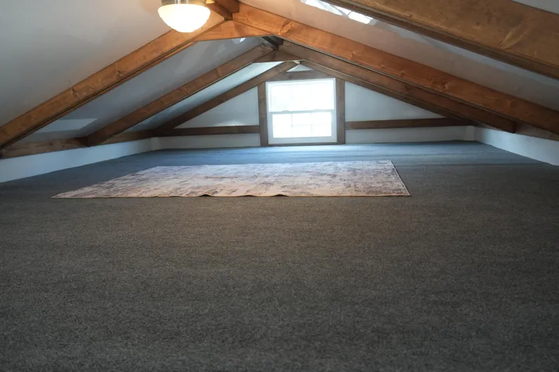 Slide: The Image of Attic space with wooden beams, carpeted floor, and a window in a 2024 Catamaran Aqua Lodge. - 41