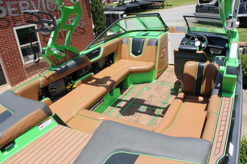Slide: The Image of 2017 Nautique Super Air Nautique G23 interior with green and tan seating, modern dashboard. - 11