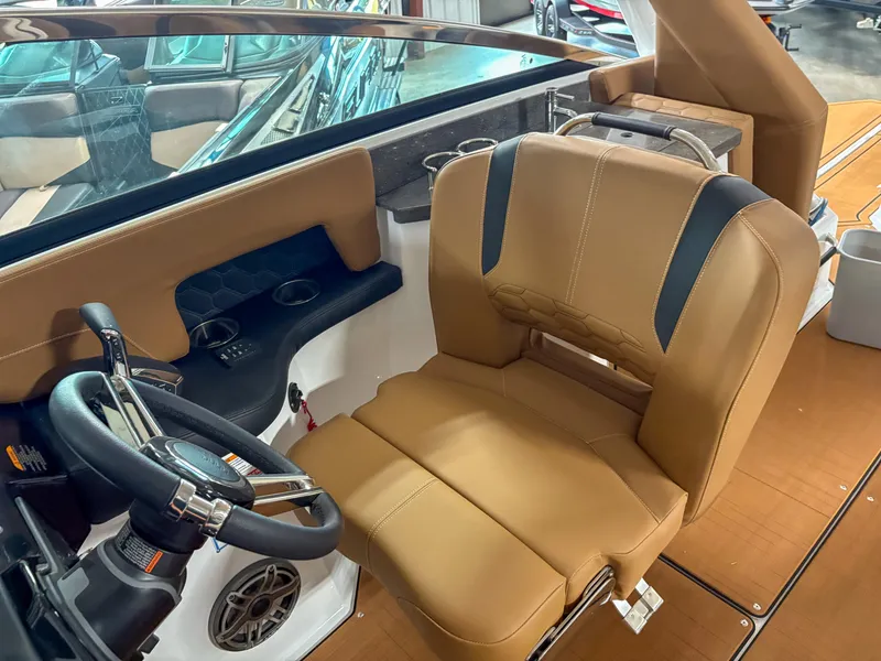 Slide: The Image of 2026 Four Winns H9 boat interior with tan leather captain's seat and steering wheel. - 11