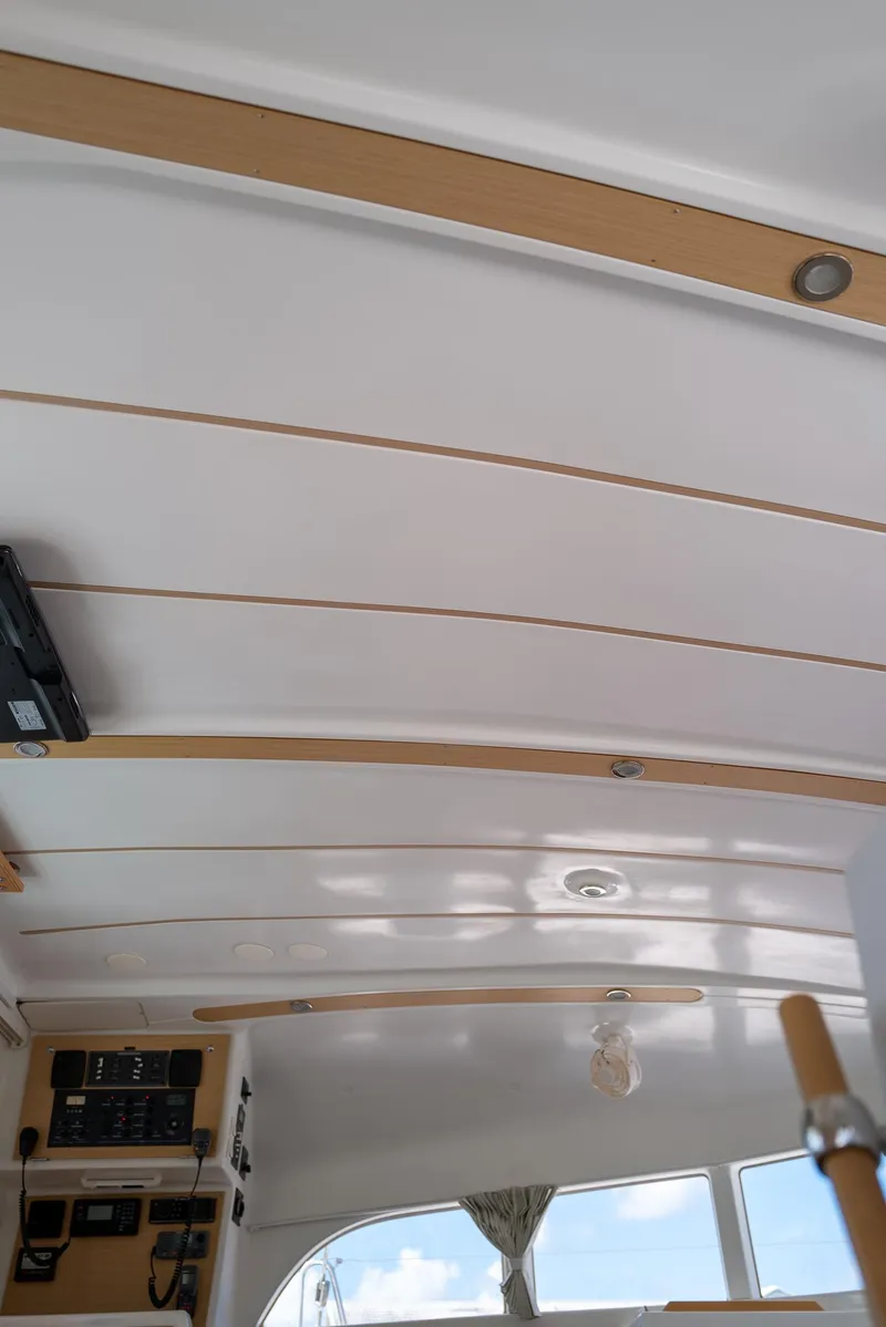 Slide: The Image of Interior ceiling of 2011 Lagoon 380 S2 catamaran with wood accents and control panels. - 16