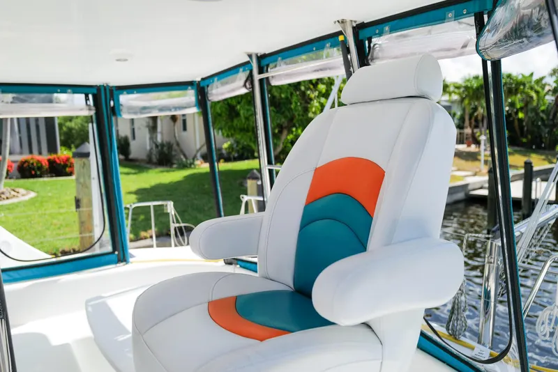 Slide: The Image of Captain's chair on 2011 Lagoon 380 S2 catamaran, featuring colorful upholstery and marina view. - 2