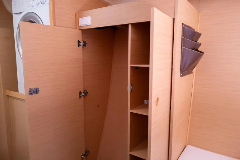 Slide: The Image of Interior of 2011 Lagoon 380 S2 yacht with open wooden cabinets and washing machine. - 22