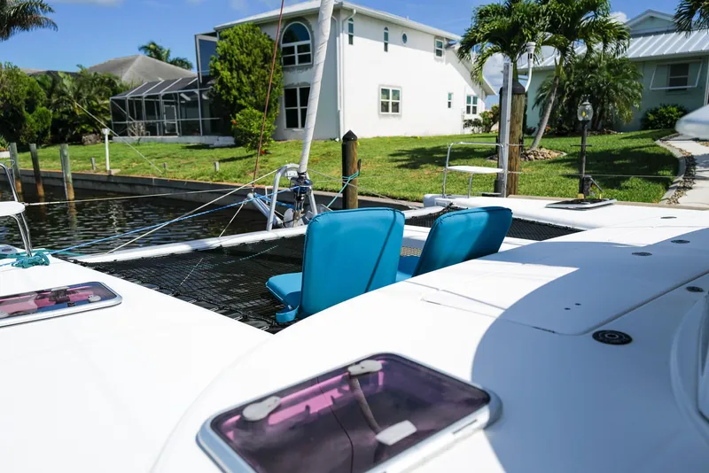 Slide: The Image of Lagoon 380 S2 catamaran, 2011 model, docked near waterfront homes with lush greenery. - 34
