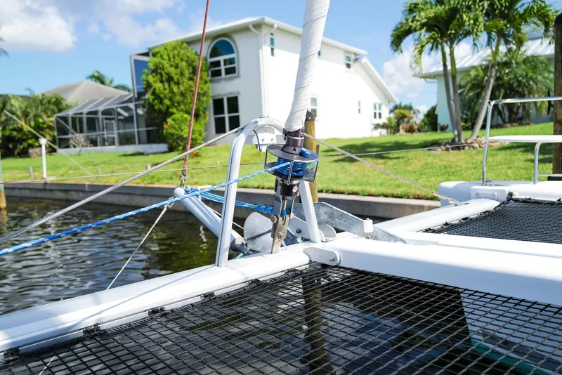 Slide: The Image of Lagoon 380 S2 catamaran detail near waterfront home, showcasing rigging and netting. - 36