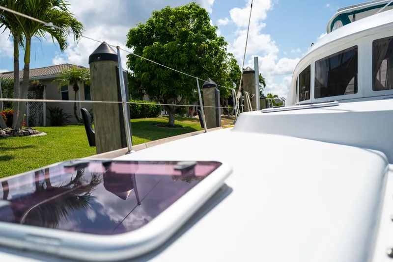 Slide: The Image of 2011 Lagoon 380 S2 yacht docked, with lush greenery and clear skies in the background. - 39