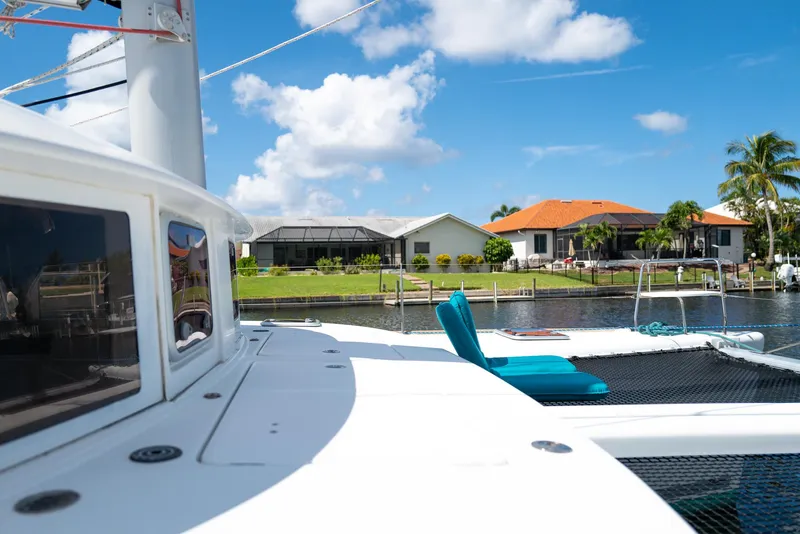 Slide: The Image of Lagoon 380 S2 catamaran docked near waterfront homes under a clear blue sky. - 40