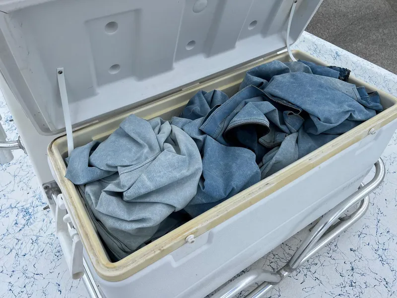 Slide: The Image of Open cooler filled with blue denim clothes on a patterned surface. - 15
