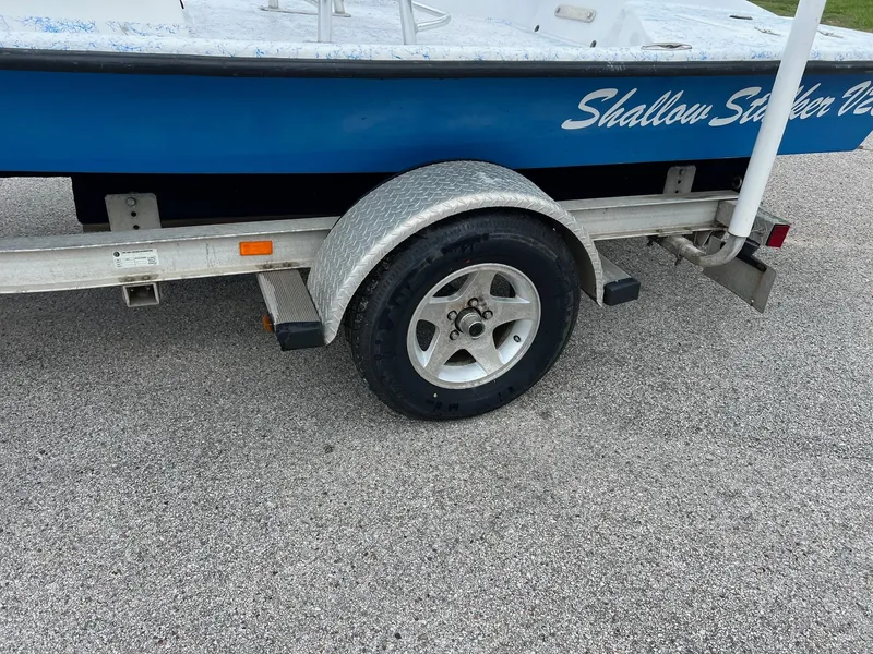 Slide: The Image of Trailer with 2007 Shallow Stalker V20 boat on pavement, featuring a visible wheel and fender. - 5