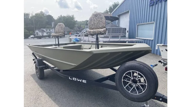 Slide: The Image of 2025 Lowe Roughneck RX1660 Tiller boat on trailer, featuring camouflage seats, parked outside. - 3