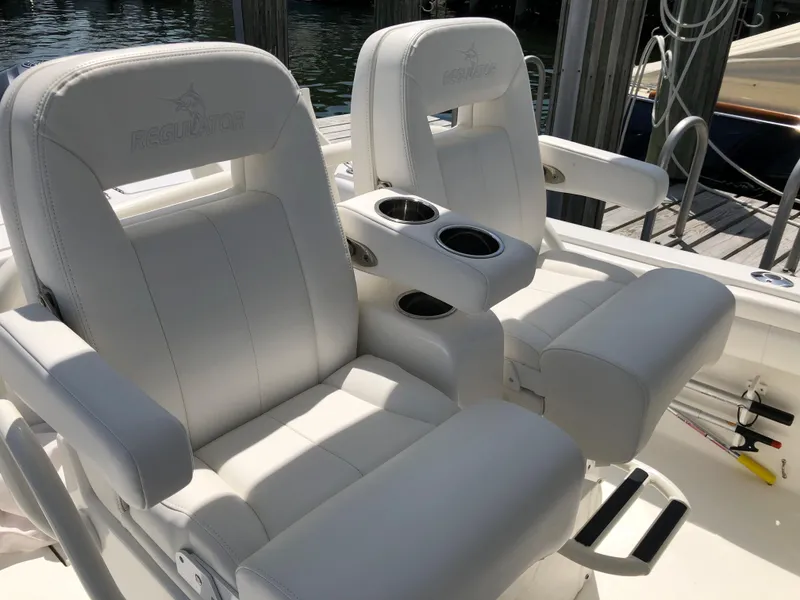Slide: The Image of 2018 Regulator 28 Center Console boat seats with cup holders, docked by water. - 8