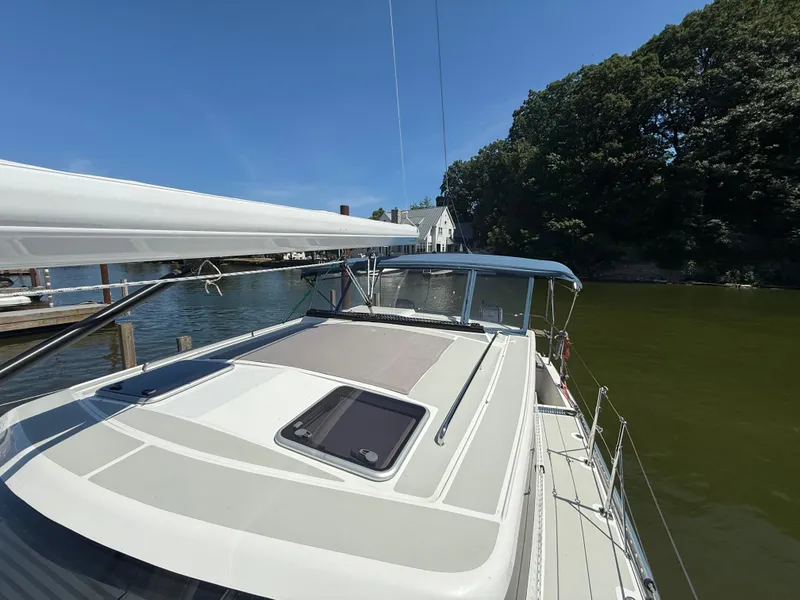 Slide: The Image of 2024 Tartan 455 sailboat docked by a serene waterfront with lush greenery. - 11