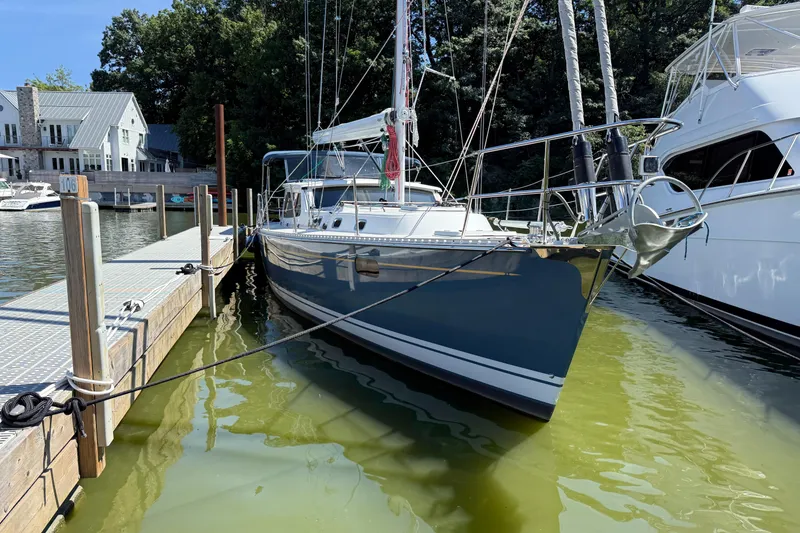 Slide: The Image of 2024 Tartan 455 sailboat docked at marina, surrounded by trees and neighboring boats. - 14