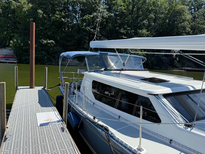 Slide: The Image of 2024 Tartan 455 yacht docked by a serene, tree-lined lake. - 3