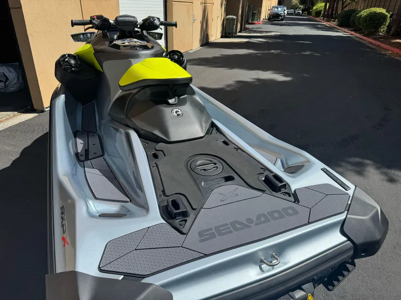 Slide: The Image of 2024 Sea-Doo RXP-X 325 jet ski, silver and yellow, parked outdoors. - 12
