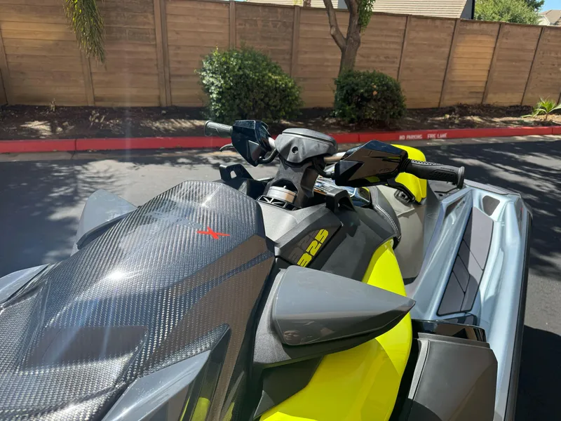 Slide: The Image of 2024 Sea-Doo RXP-X 325 jet ski, vibrant yellow and black design, parked outdoors. - 2