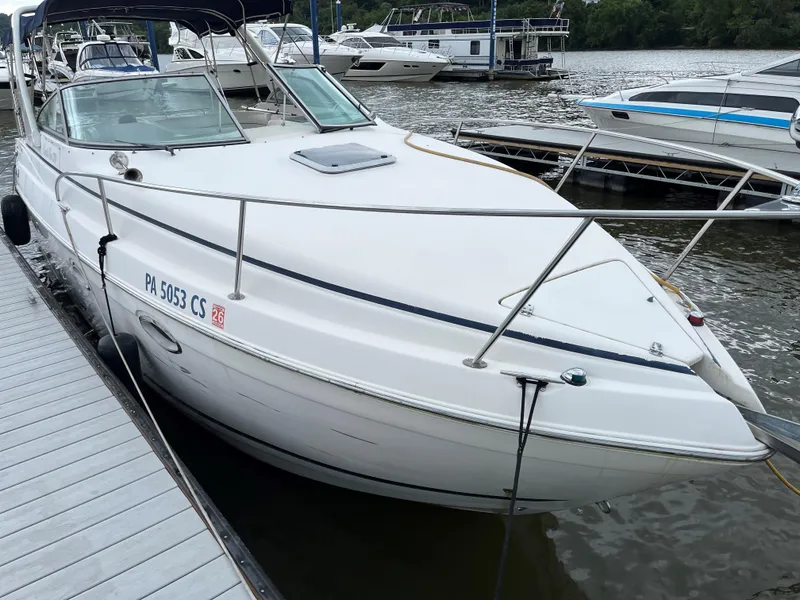 The Image of 2004 Rinker Fiesta Vee 270 boat docked at marina, white exterior, calm water background. - 1