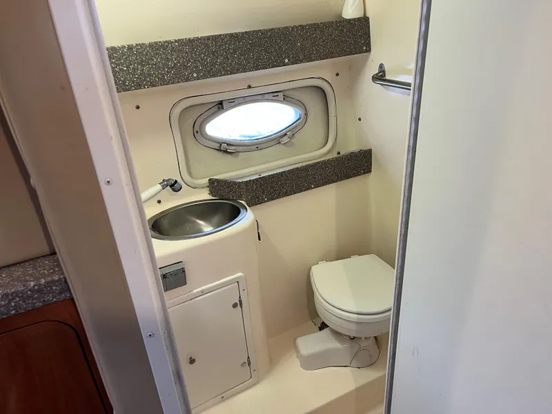Slide: The Image of 2004 Rinker Fiesta Vee 270 boat bathroom with sink, toilet, and porthole window. - 8