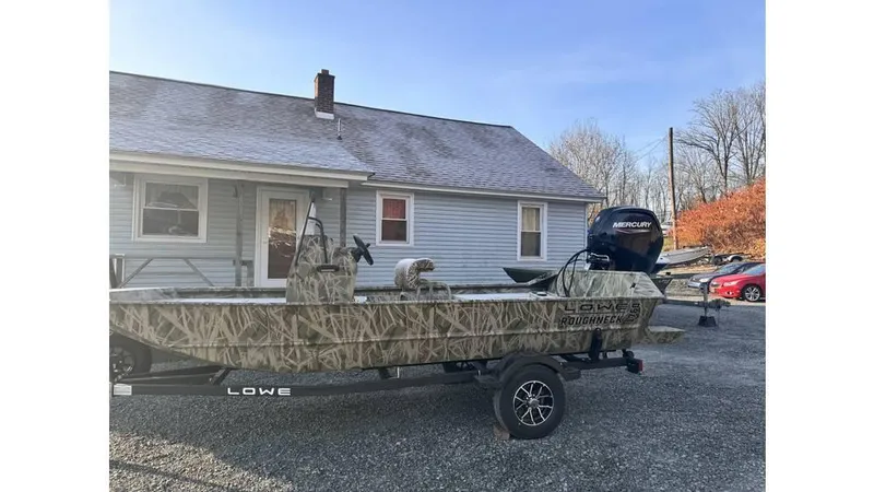 Slide: The Image of 2025 Lowe Roughneck RX1760 Pathfinder boat on trailer, parked in front of a house. - 10
