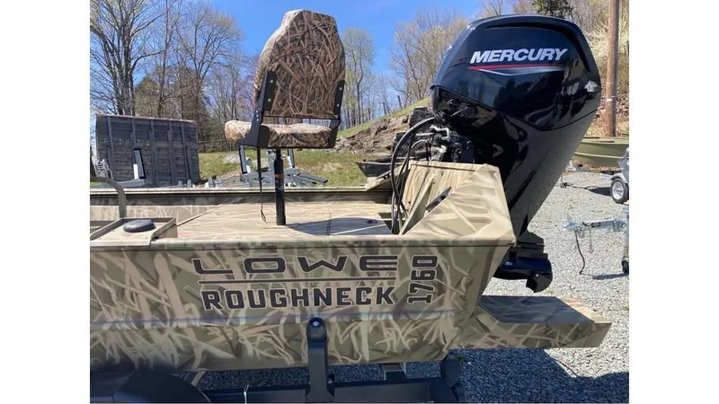 Slide: The Image of 2025 Lowe Roughneck RX1760 Pathfinder boat with Mercury engine, camo design, outdoor setting. - 3