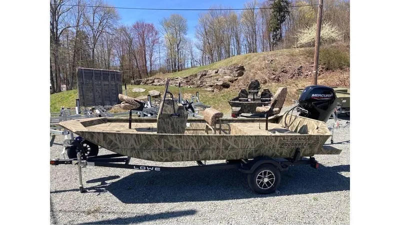 Slide: The Image of 2025 Lowe Roughneck RX1760 Pathfinder boat on trailer, camo design, parked outdoors. - 5