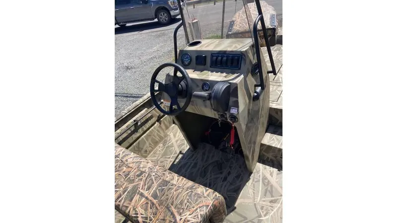 Slide: The Image of 2025 Lowe Roughneck RX1760 Pathfinder boat interior with camouflage design and steering console. - 6