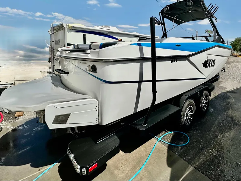 Slide: The Image of 2024 Axis T250 boat on trailer, sleek design, white and blue accents, parked outdoors. - 3