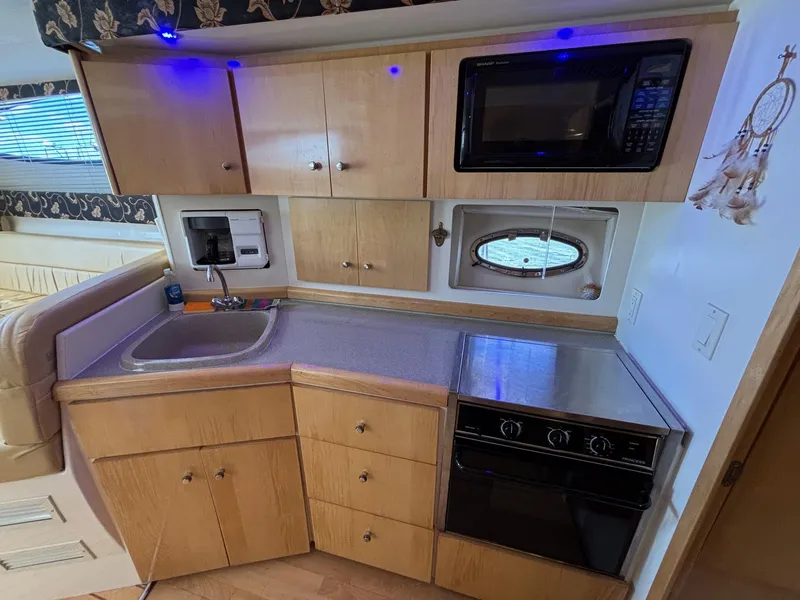 Slide: The Image of 2001 Carver 350 Mariner kitchen with sink, microwave, stove, and wooden cabinets. - 17