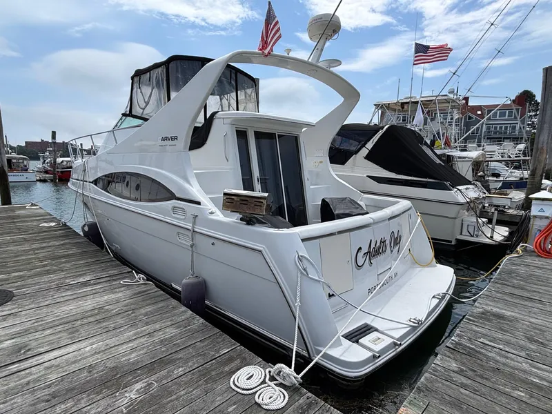 Slide: The Image of 2001 Carver 350 Mariner yacht docked at marina, American flags waving, clear sky. - 2