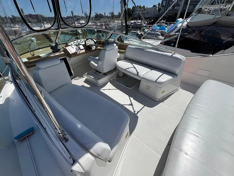 Slide: The Image of 2001 Carver 350 Mariner yacht interior with white seating and steering area in a marina. - 6