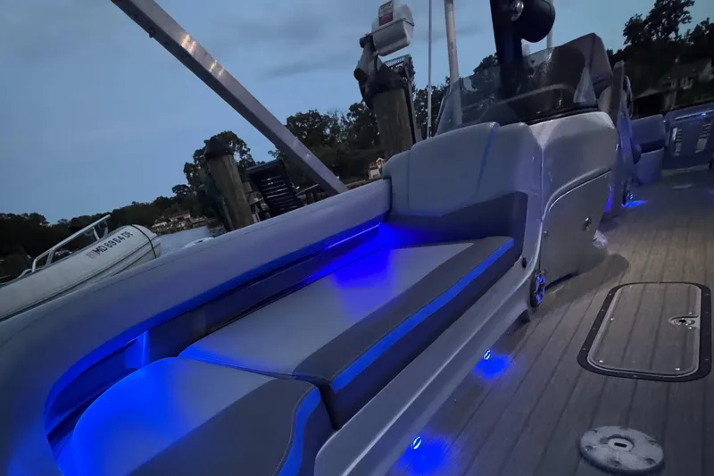 Slide: The Image of 2021 Manitou 25 XT SRS boat interior with blue LED lighting at dusk. - 12