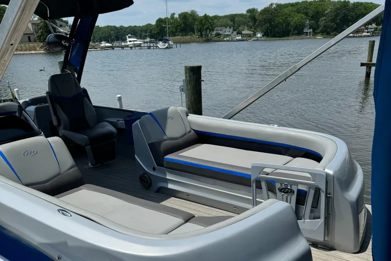 Slide: The Image of 2021 Manitou 25 XT SRS pontoon boat interior with seating, docked by a serene lake. - 14