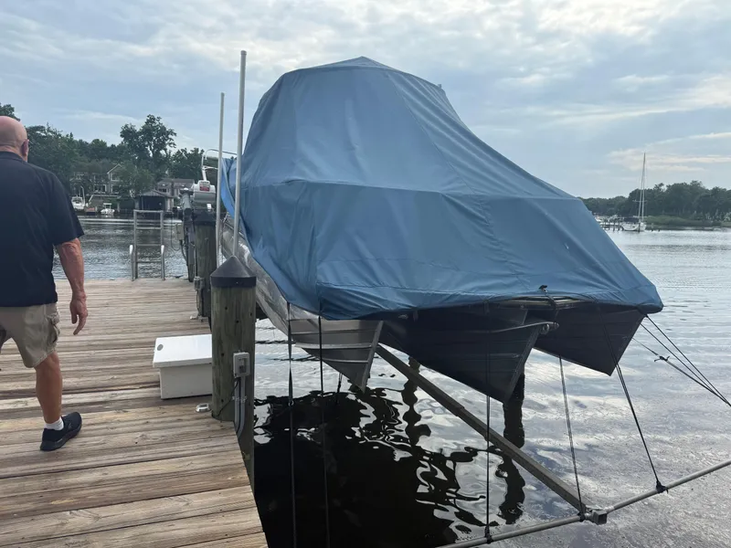 Slide: The Image of 2021 Manitou 25 XT SRS boat covered with blue tarp on dock. - 15