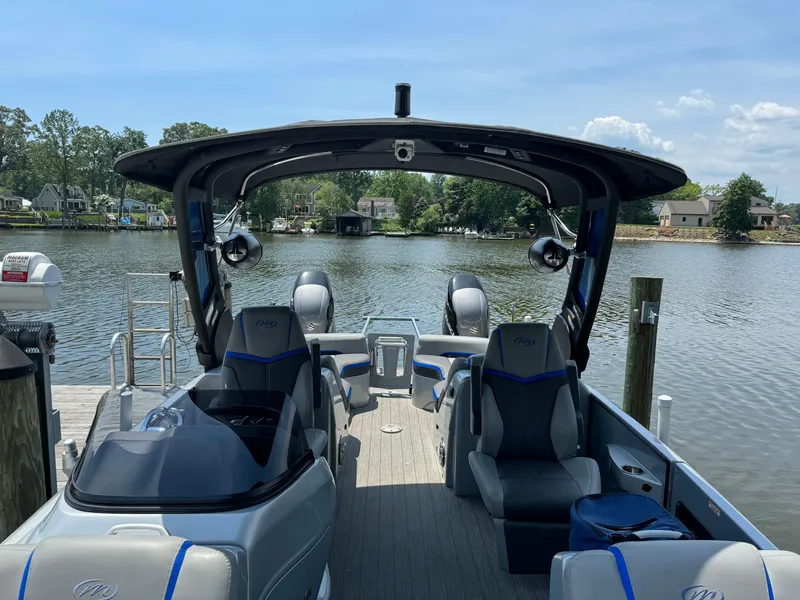 Slide: The Image of 2021 Manitou 25 XT SRS pontoon boat docked on a serene lake. - 2