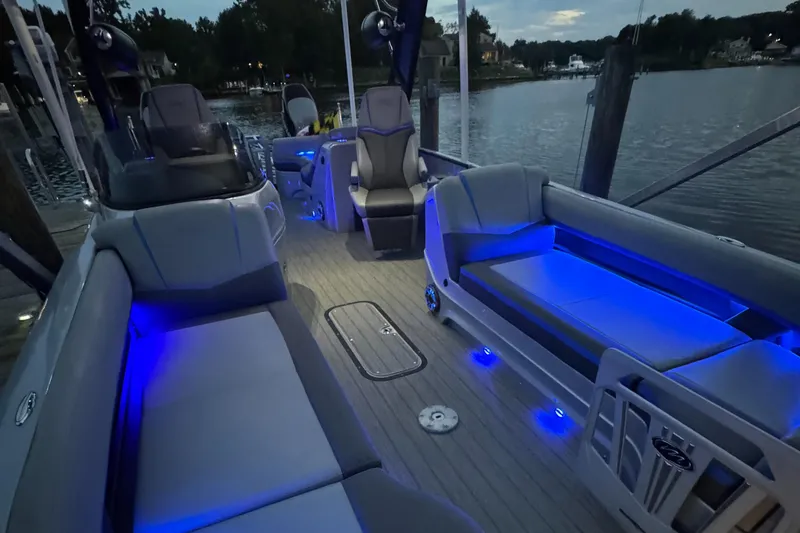 Slide: The Image of 2021 Manitou 25 XT SRS pontoon boat interior with blue LED lighting at dusk. - 7