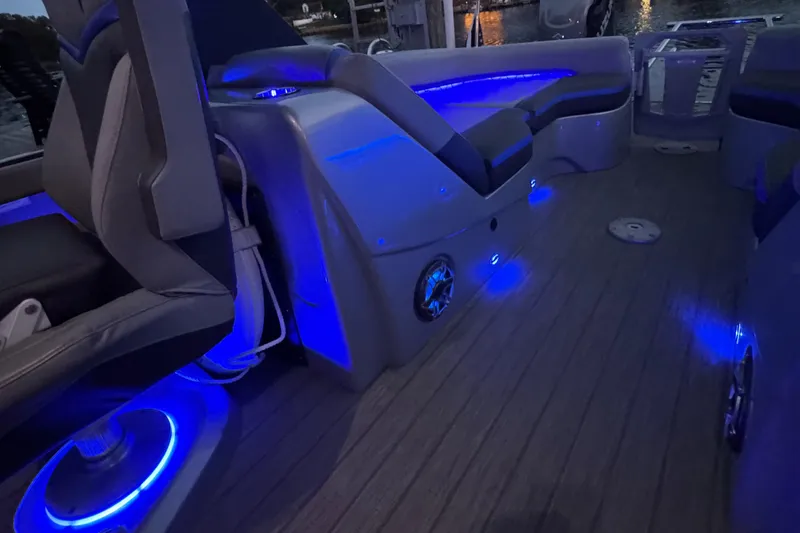 Slide: The Image of 2021 Manitou 25 XT SRS boat interior with blue LED lighting and luxurious seating. - 9