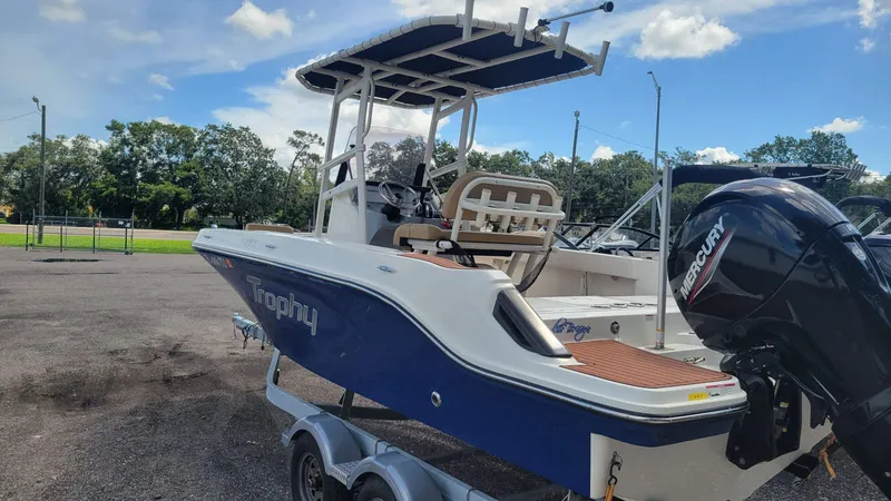 Slide: The Image of 2024 Trophy T20CC boat with Mercury engine on trailer, parked outdoors. - 11