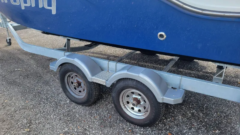 Slide: The Image of 2024 Trophy t20cc boat on a dual-axle trailer, parked on gravel. - 12