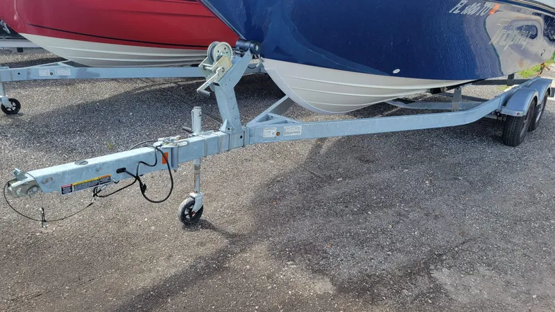 Slide: The Image of 2024 Trophy t20cc boat trailer on gravel, featuring sturdy metal frame and wheels. - 13