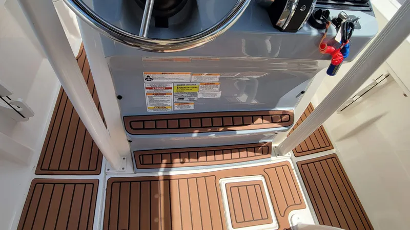 Slide: The Image of 2024 Trophy T20CC boat console with steering wheel and teak-style flooring. - 30
